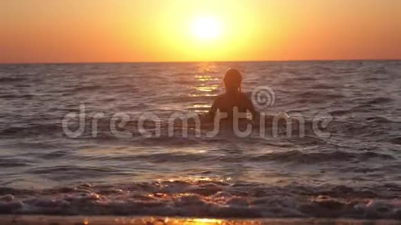 女人在令人惊叹的日落时分在海里玩水节假日期间自由度假旅游慢动作1920x1080视频的预览图