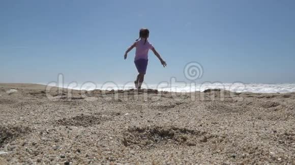 无忧无虑的快乐女孩张开双臂奔跑在沙滩上视频的预览图