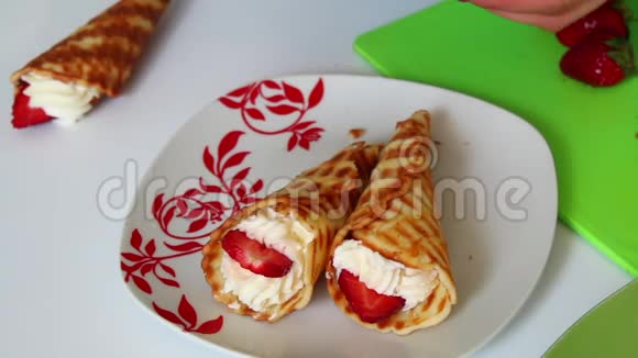 一个女人把牛角放在盘子里上面放着奶油上面装饰着草莓视频的预览图