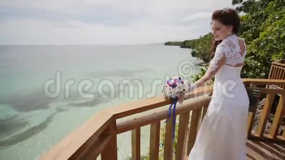 一位耀眼的新娘从俯瞰海洋和珊瑚礁的阳台高度享受幸福失去爱异国情调视频的预览图