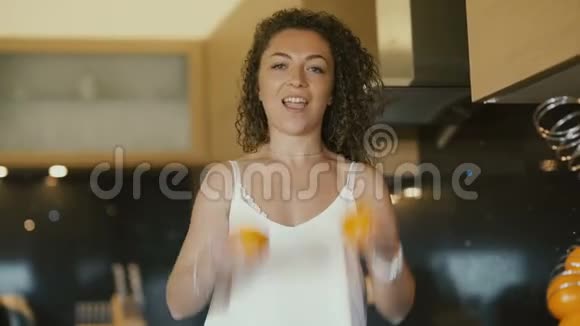 有趣的卷发女孩在厨房里用橙子视频的预览图