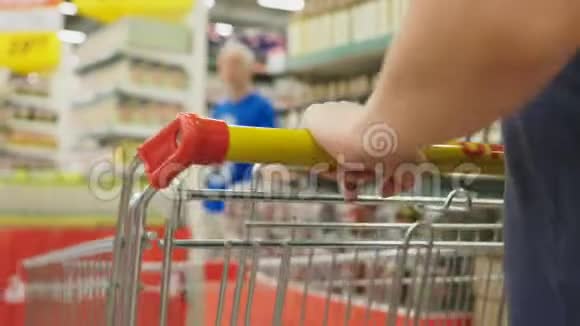 超市里的一个女人正从柜台边经过篮子一个女人在超市里走来走去特写镜头视频的预览图
