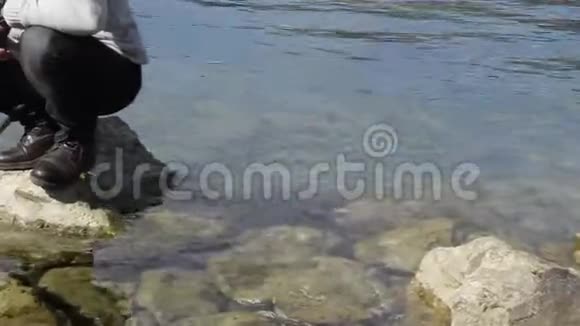 海岩上的人用渔网在水中的低视角视频的预览图