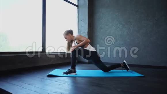 年轻的健身妇女做腿部伸展运动健身房里的场景穿运动服的女人视频的预览图