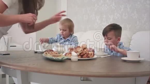 两个小男孩在桌旁喝着带有糕点的茶视频的预览图