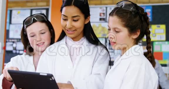 微笑的学校女生在实验室讨论数字平板电脑视频的预览图