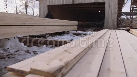 在锯木厂院子里存放的一堆堆积的木材上工作的人视频的预览图