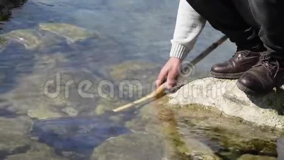 海岩上的人用渔网在水中的低视角视频的预览图