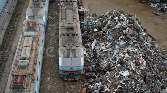 大堆的金属废料和带垃圾的集装箱在白天多云天气的火车附近视频的预览图