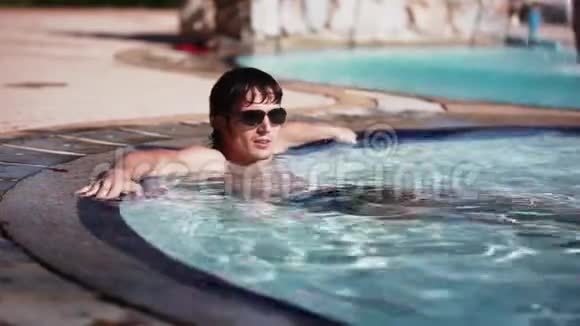 戴太阳镜的英俊的年轻人躺在游泳池里休息幸福暑期旅游度假酒店1920x1080视频的预览图