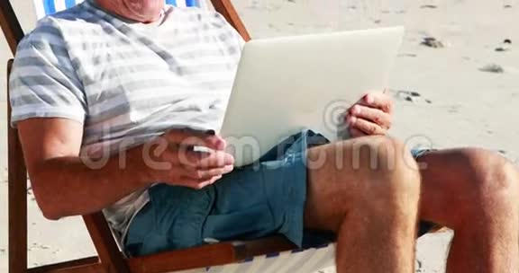 在沙滩上用笔记本电脑聊天的老人视频视频的预览图