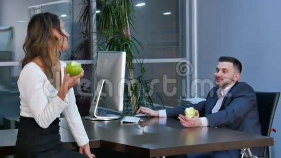 两名办公室工作人员休息吃着绿苹果在办公室里聊天视频的预览图