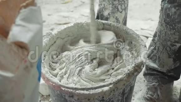 用电动搅拌器将白灰泥混合在桶中视频的预览图