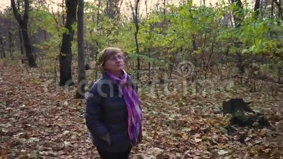 老年妇女在秋天的森林里散步视频的预览图