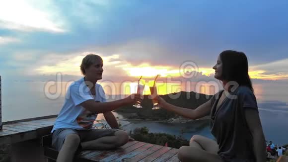 年轻浪漫的情侣在咖啡馆的露台上举杯祝酒欣赏日落视频的预览图