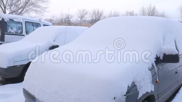 被雪覆盖的汽车在严重的冬季风暴下在雪下的院子里视频的预览图