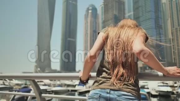 一个快乐的女孩在迪拜的摩天大楼背景下迪拜码头视频的预览图