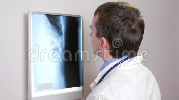 一位年轻的医生在墙上检查一位病人X光检查结果胸部和肋骨的分析视频的预览图