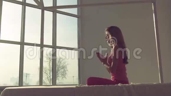 可爱平静的女人坐在莲花姿势下练习瑜伽视频的预览图