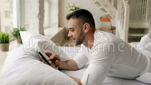 年轻有魅力的男人躺在床上而他的女朋友早上在卧室里拥抱他视频的预览图