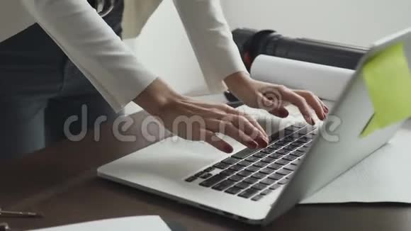 特写镜头年轻的女建筑师手提电脑和办公桌面上的蓝图视频的预览图