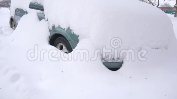 被雪覆盖的汽车在严重的冬季风暴下在雪下的院子里视频的预览图