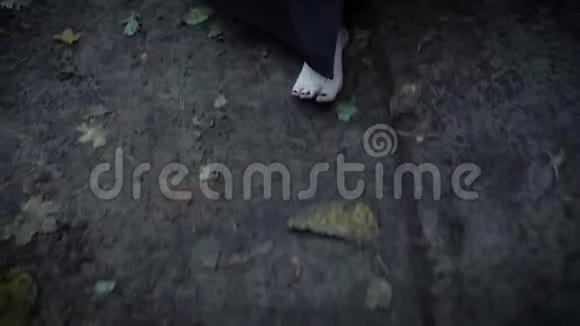 一个光着脚走在灰色的公园路上的女人一个穿着一件长裙子的女人的近景视频的预览图