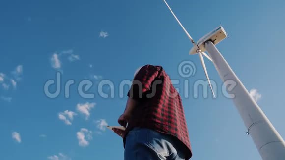 风车发电厂工程师手持平板电脑天空背景视频的预览图
