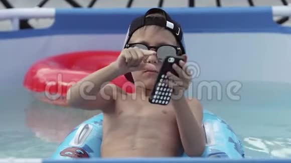 这个男孩正在打电话在游泳池里放松视频的预览图