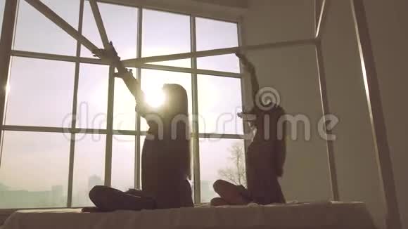 两个身材苗条的女人在窗口背景下做瑜伽视频的预览图