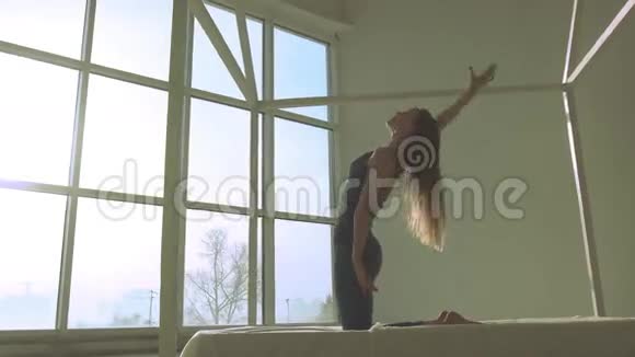 阳光明媚的早晨年轻女子在灯光明亮的房间里练瑜伽视频的预览图