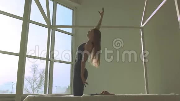 在光线充足的房间里做瑜伽的皮肤白皙的女人视频的预览图