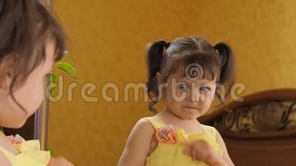 一个小女孩在照镜子一个头上有尾巴的漂亮女孩正在研究猫头鹰的脸一个穿黄色制服的孩子视频的预览图