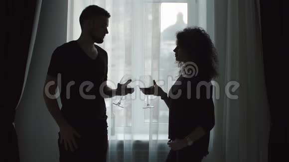 喝葡萄酒的情侣的剪影站在窗前视频的预览图