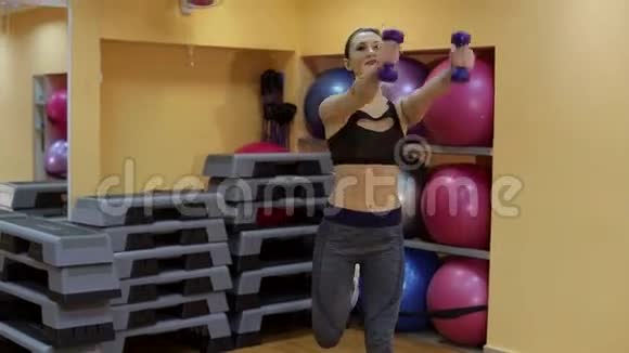 女孩在健身房用哑铃做阶梯有氧运动视频的预览图