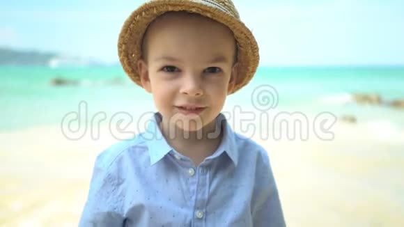 在海滩上戴草帽的可爱男孩肖像视频的预览图