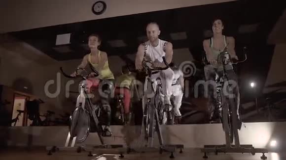 一群喜欢运动的年轻人在晚上骑固定自行车锻炼视频的预览图