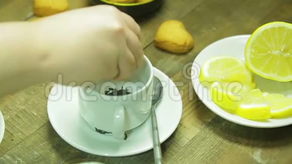 女人的手在白色的杯子里倒红茶视频的预览图