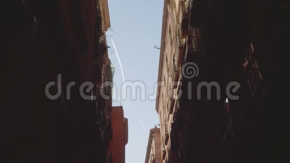 在建筑物之间狭窄的直线上天空中的飞机轨迹的底部视图视频的预览图