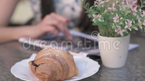 背景牛角面包花女人用电话在桌子上视频的预览图