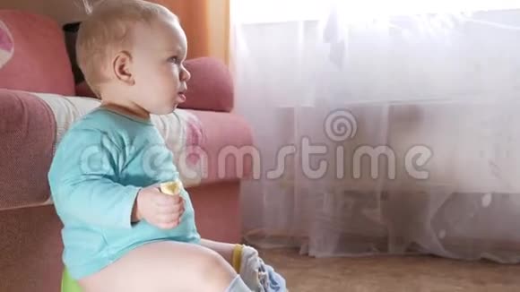 一个2岁有魅力的男孩坐在家里的锅上吃香蕉仔细看着电视视频的预览图