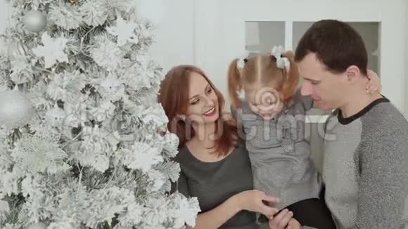 一家人站在圣诞树附近一边笑着说着一边摸着玩具一边等待圣诞节视频的预览图