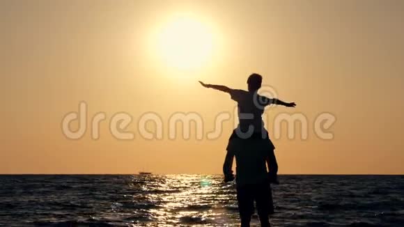 幸福家庭的剪影父子俩在海边的夜空中玩耍两个人的剪影视频的预览图
