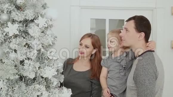 一家人站在圣诞树附近一边笑着说着一边摸着玩具一边等待圣诞节视频的预览图