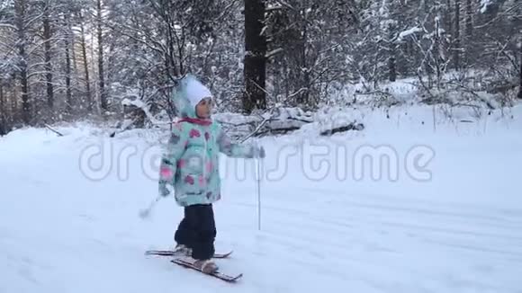 女孩正在学习滑雪她在松软的雪地里慢慢地滑上滑雪板冬天森林里美丽的一天走进去视频的预览图