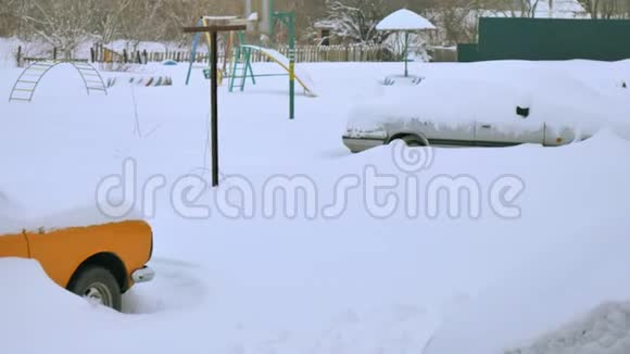 被雪覆盖的汽车在严重的冬季风暴下在雪下的院子里视频的预览图