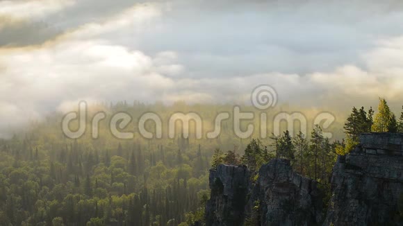 云在松树高地森林和岩石上移动乌拉尔山的雾状晨景视频的预览图