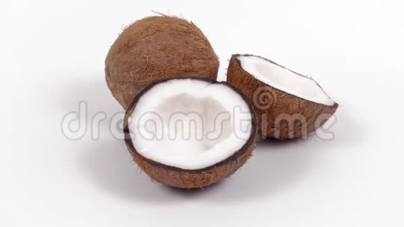 一整个椰子和两半美味的果肉旋转在白色孤立的背景可循环无缝视频的预览图