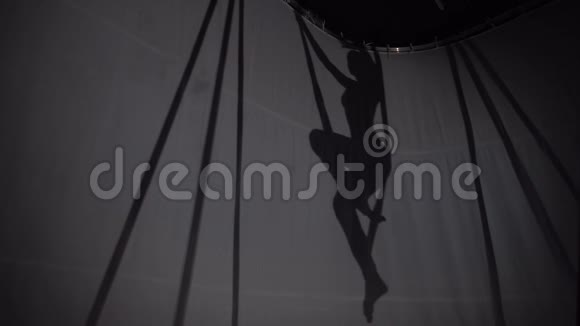 一个身材苗条的女孩坐在吊床上做瑜伽的剪影视频的预览图