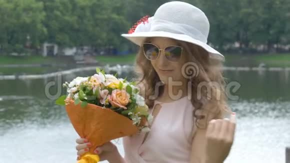 一个戴太阳镜和戴着花的白帽子的漂亮女孩的肖像特写视频的预览图